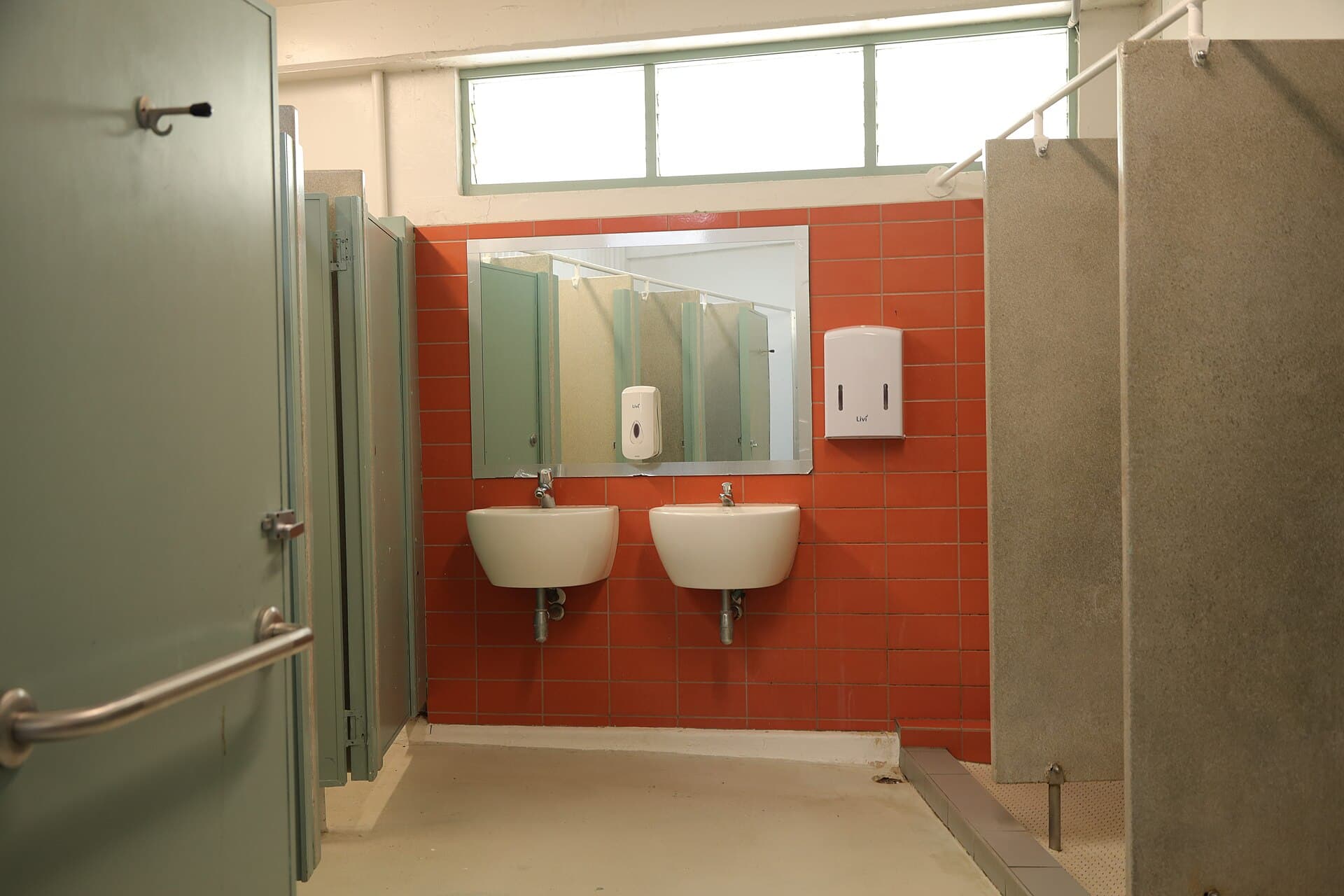Changing-room showers and washbasins behind a tiled wall.