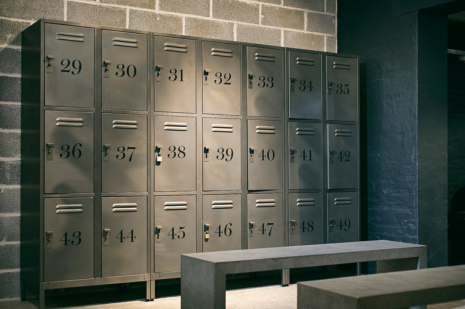 Numbered steel lockers and a concrete bench in the changing area.
