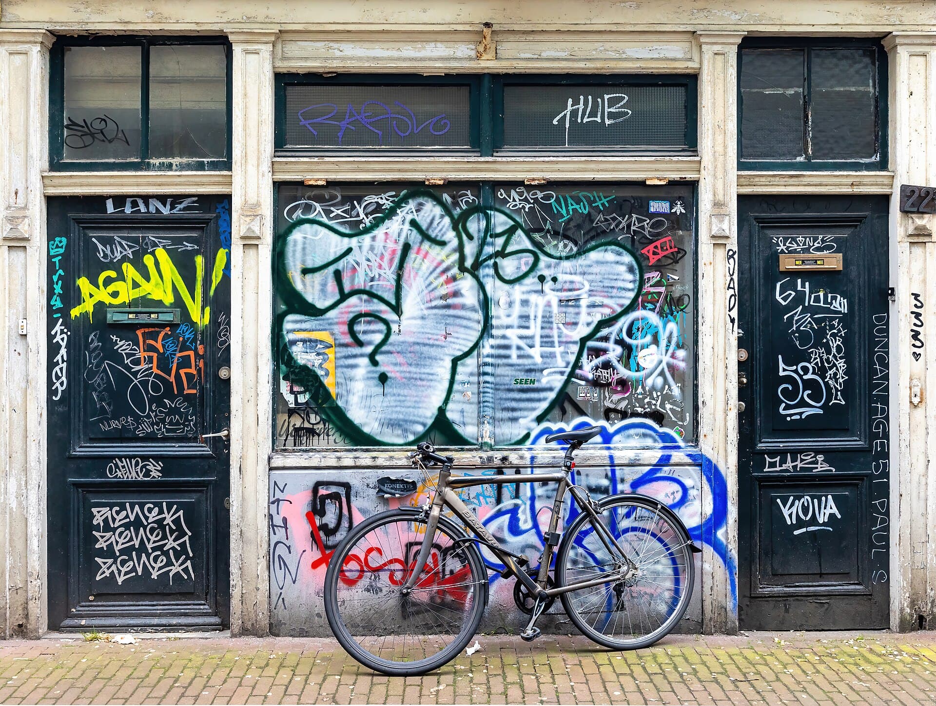 A bicycle parked against a graffiti-marked Amsterdam façade.